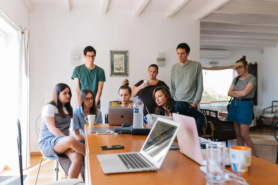 Photo of a group of people viewing a laptop screen.