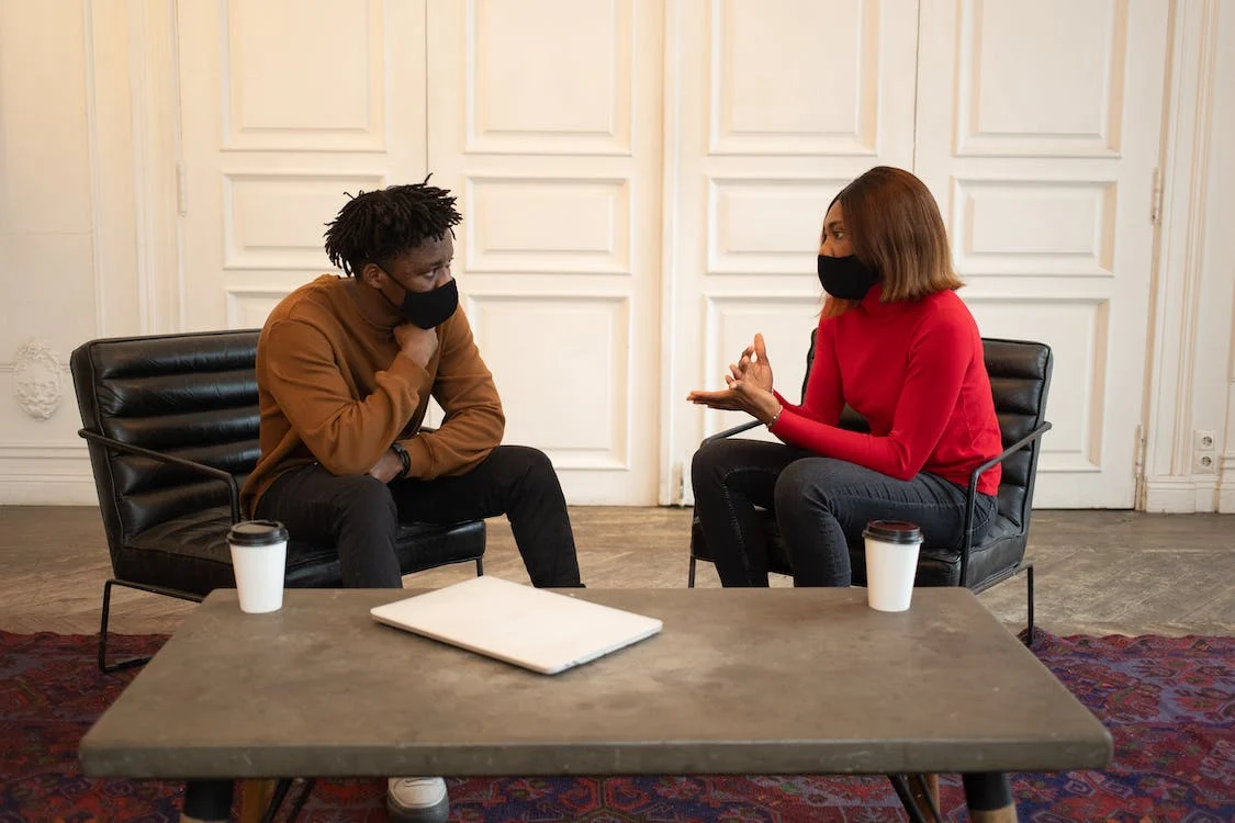 Two people wearing masks having a conversation.