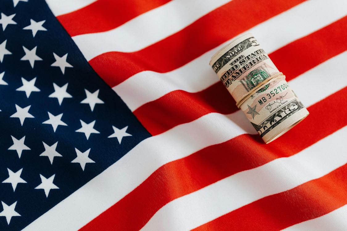 Image of the American flag with money in a roll.