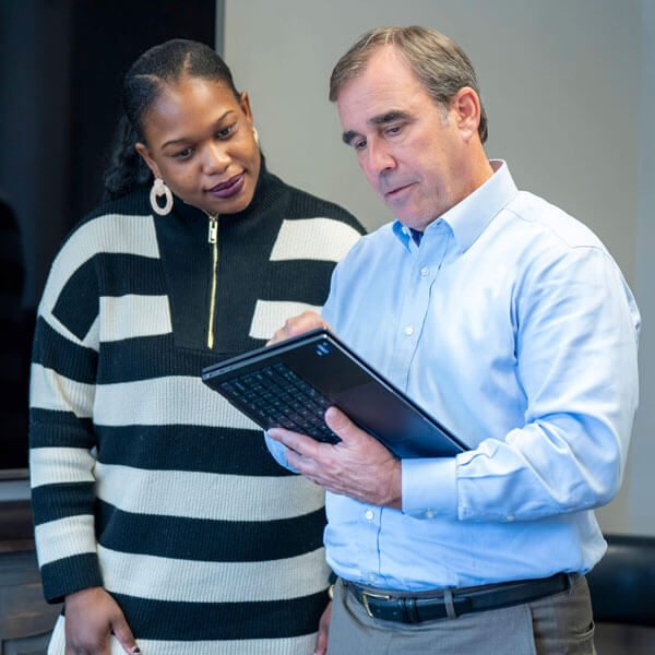 A woman and man reviewing tablet in an office conference room.