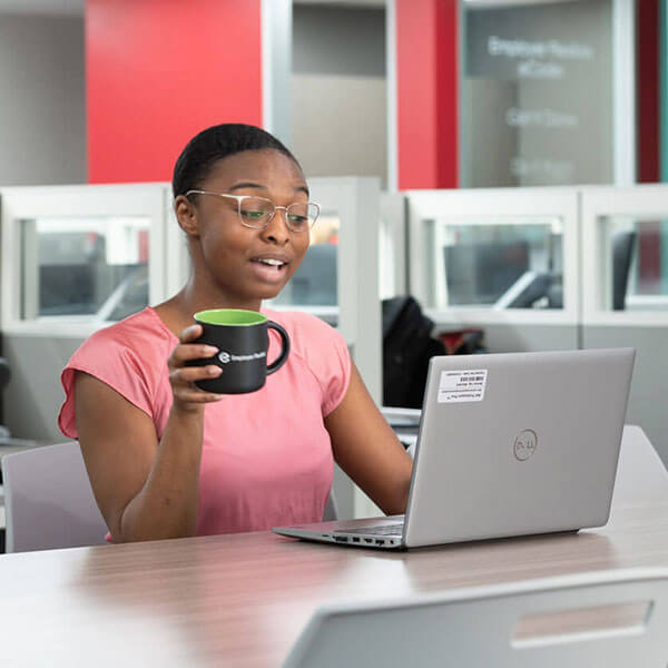 A woman at a desk, on a laptop, in a virtual meeting.