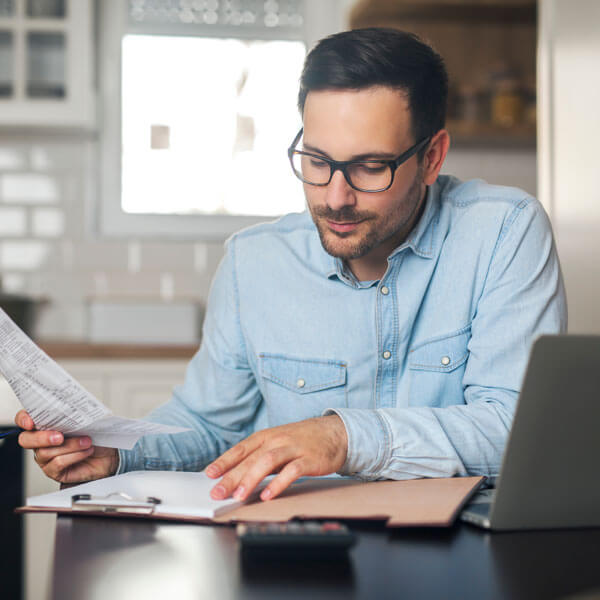 A man working with papers and a laptop.