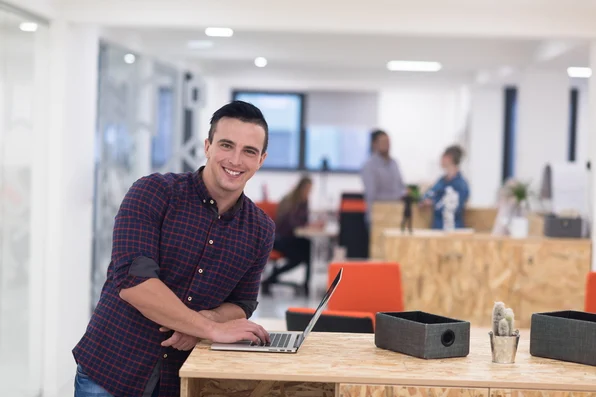 Photo of young business man in casual clothes working on laptop.