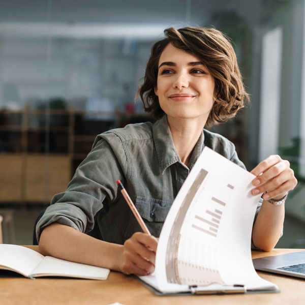 A smiling woman actively listening and taking notes.